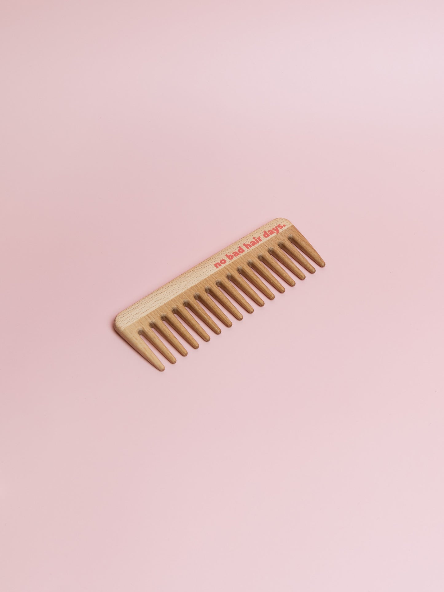 Langer Holzkamm mit groben Zinken und "no bad hair days." Druck in rot-pink