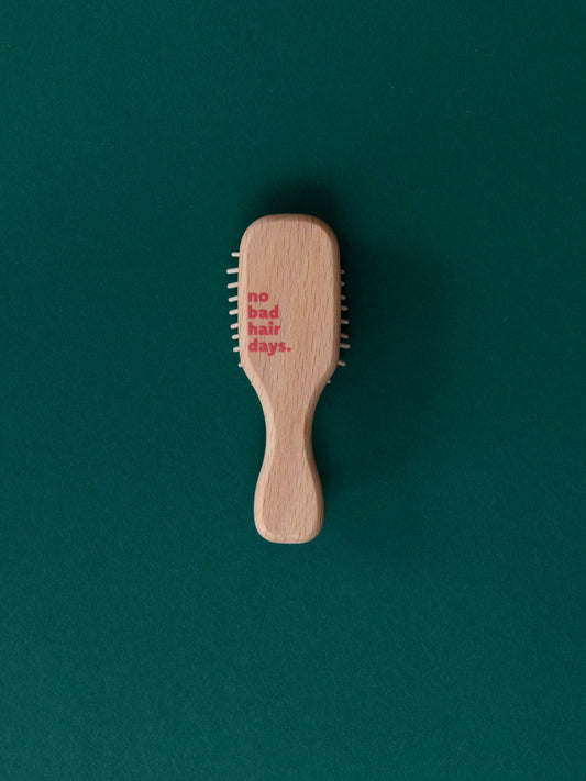 Rückseite der mini Bürste aus Holz mit "no bad hair days." Druck in rot-pink